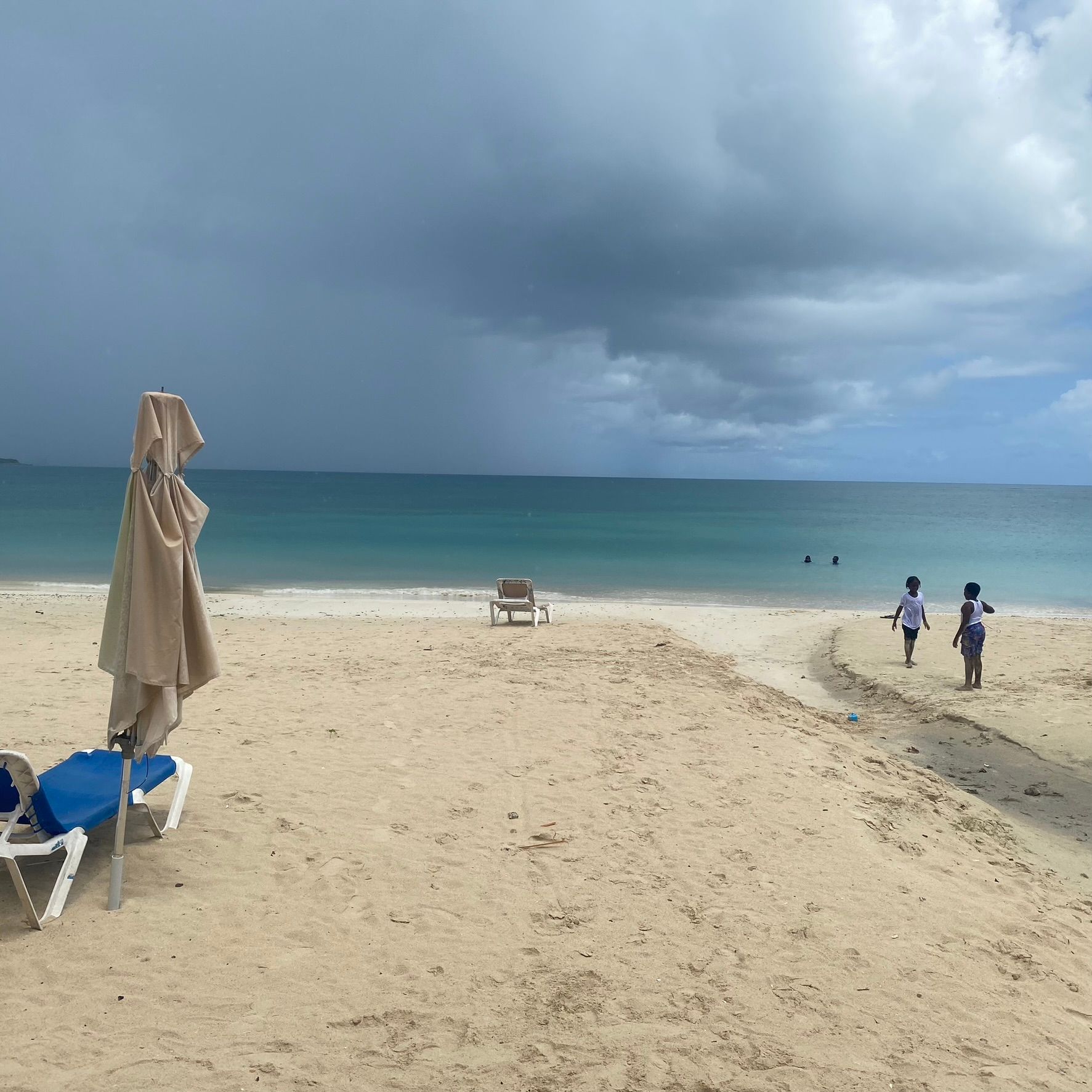 People walking on a beach with umbrellas and chairs