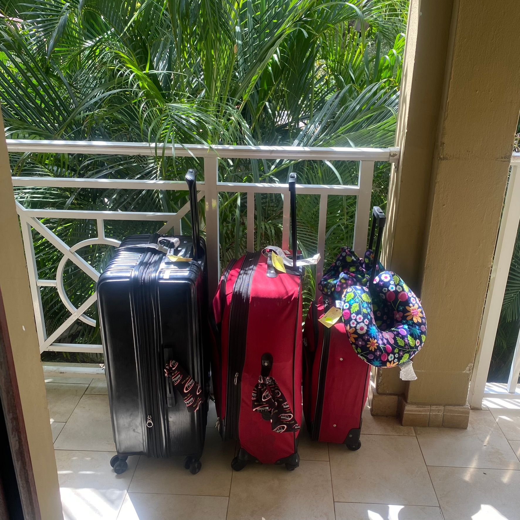 Three suitcases are sitting on a balcony with trees in the background