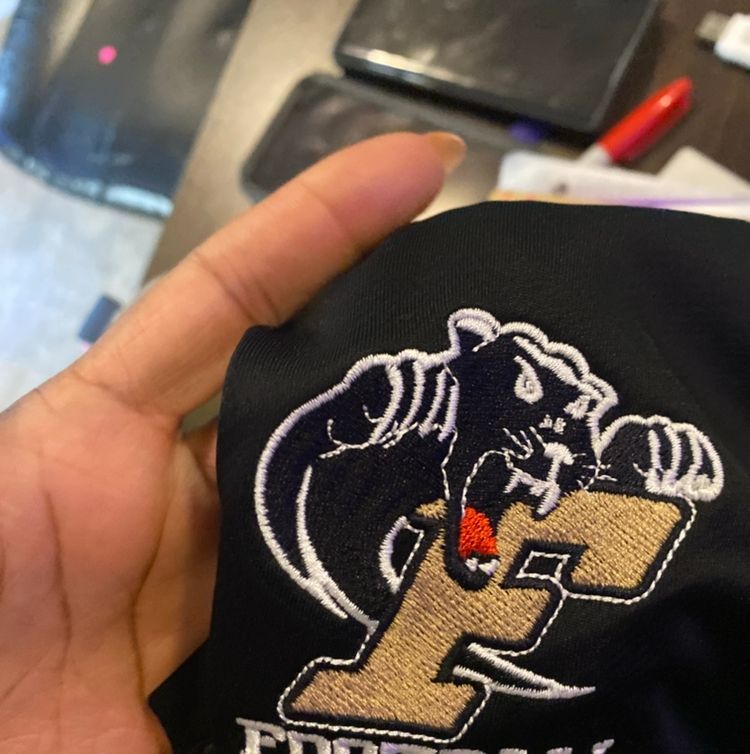 A person is holding a black shirt with the letter f on it