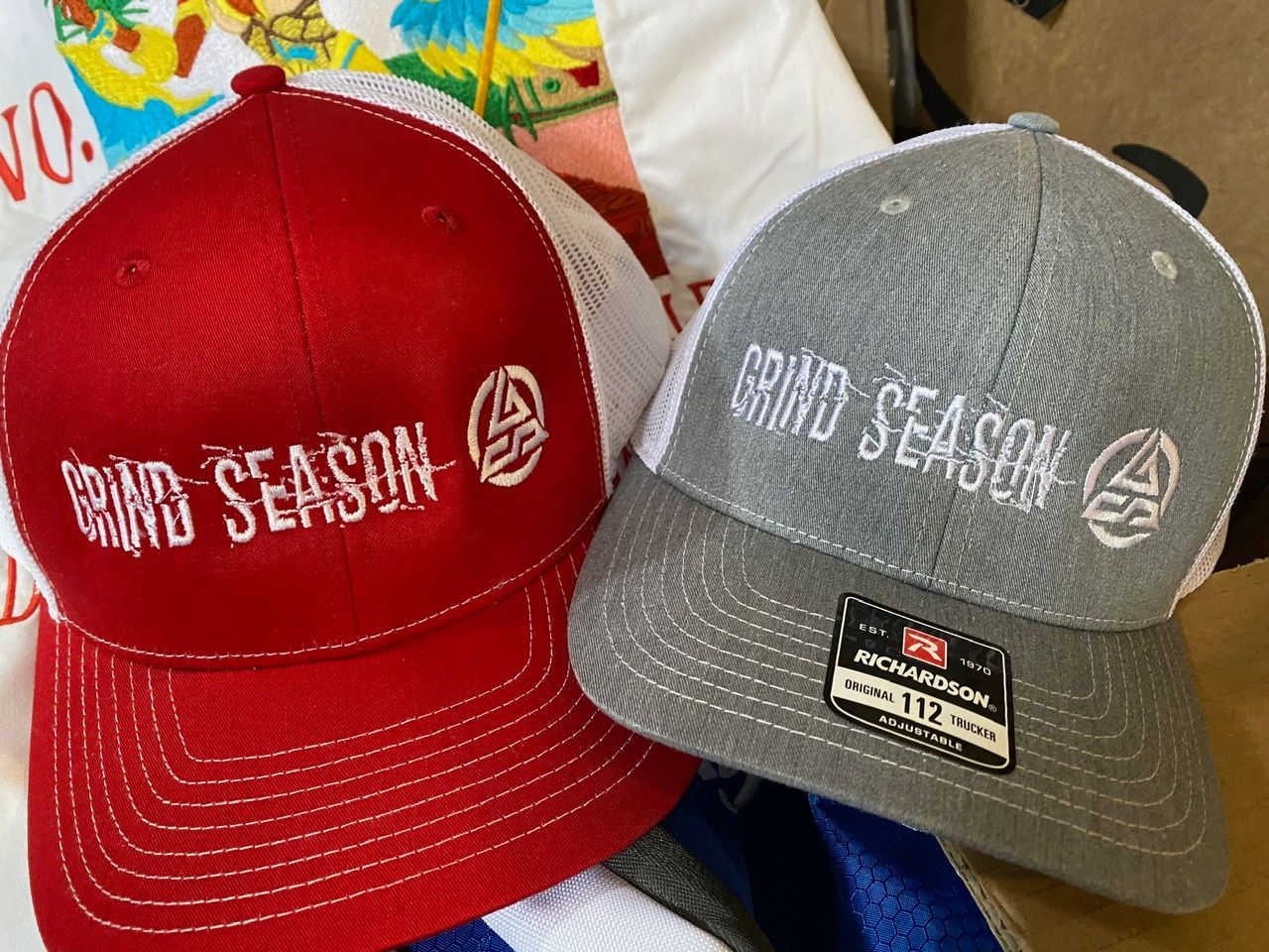 A red and gray baseball cap with grind season written on it