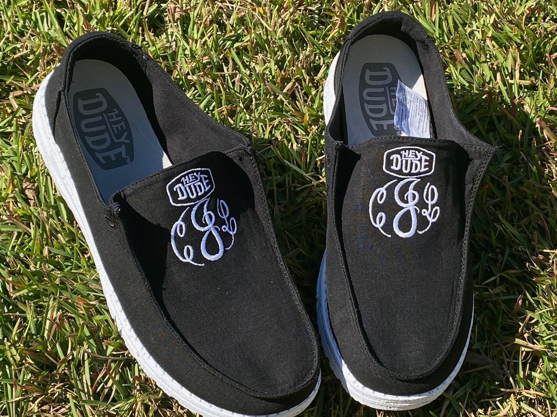 A pair of black shoes with a monogram on them