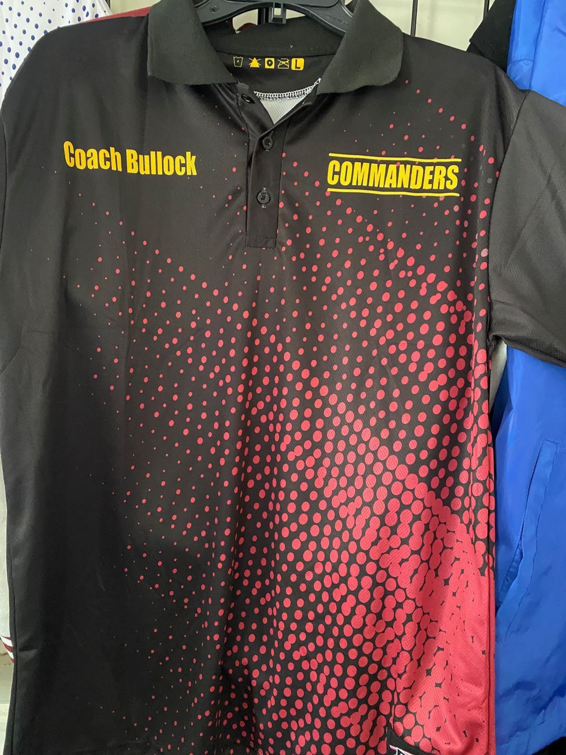 A black and red commanders polo shirt is hanging on a rack