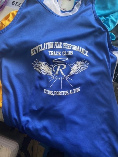 A blue shirt that says revelation peak performance track club