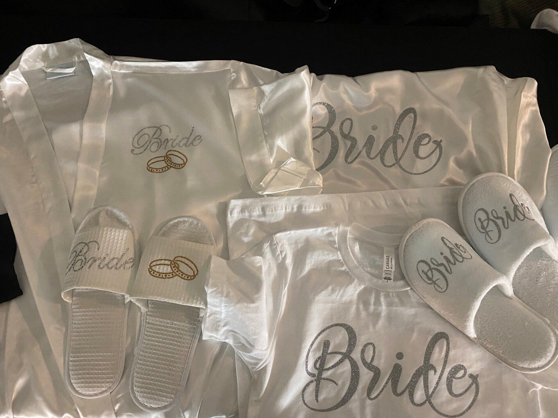 A bride 's robe and slippers are sitting on a bed.