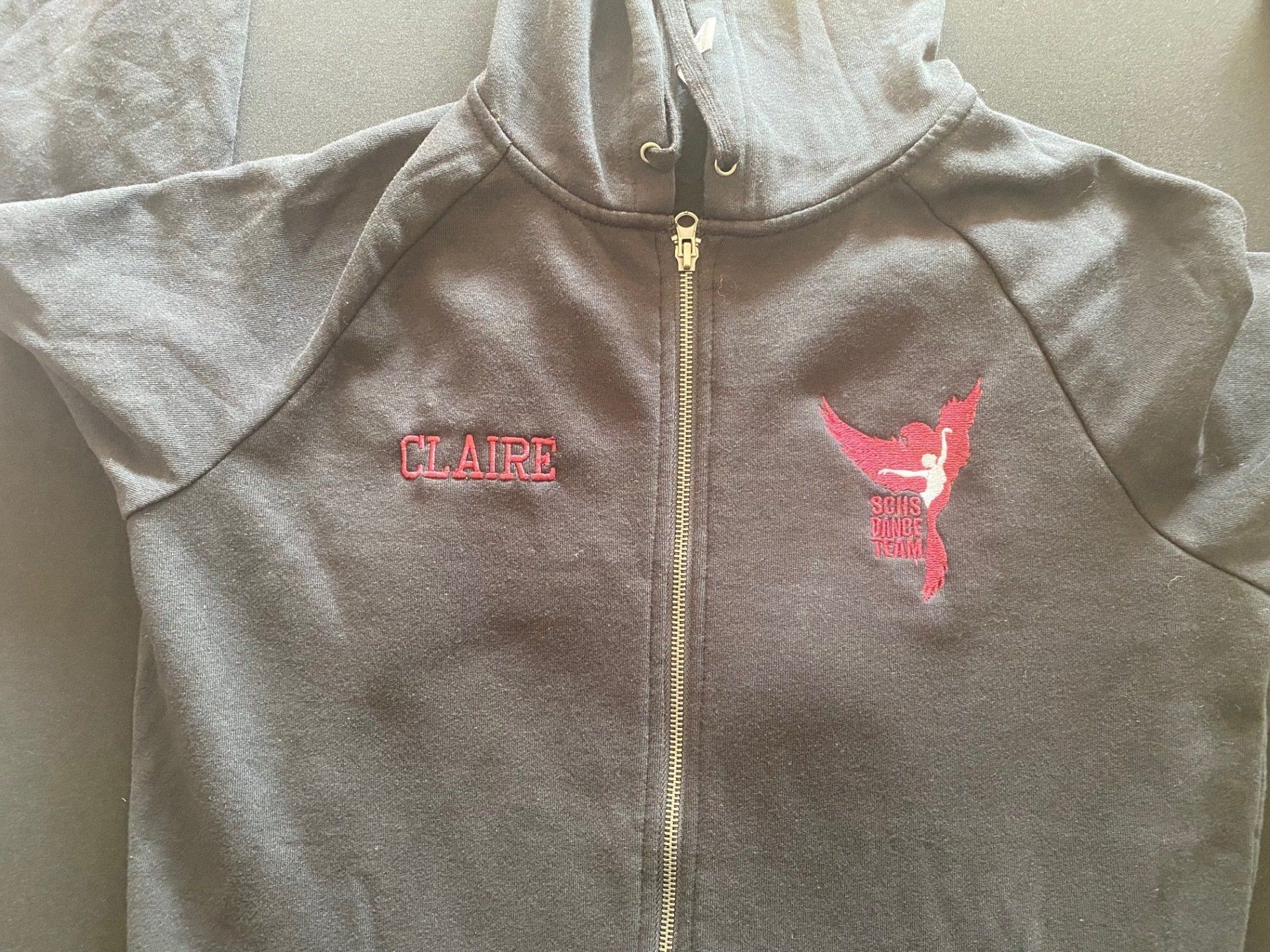 A black hoodie with a red logo on it is sitting on a table.