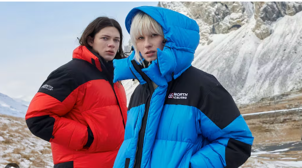 A woman in a blue jacket is standing next to a woman in a red jacket.