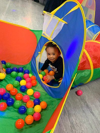 A baby is playing in a ball pit with balls.