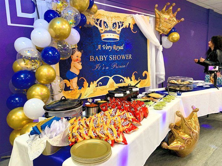 A buffet table with food and balloons for a baby shower.