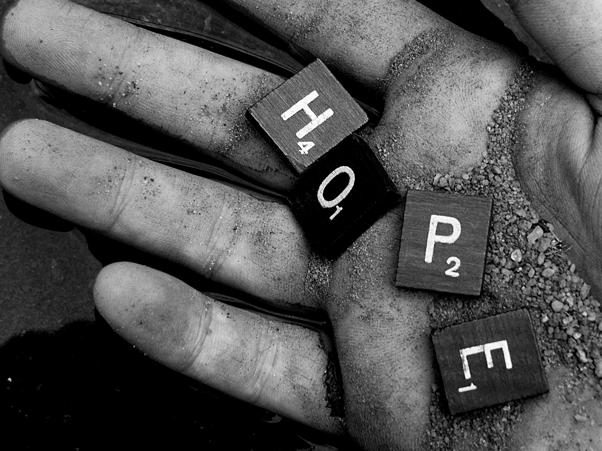 A hand holding scrabble tiles spelling 