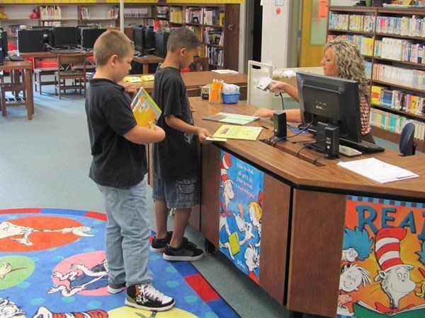 two boys are standing in front of a desk that says read