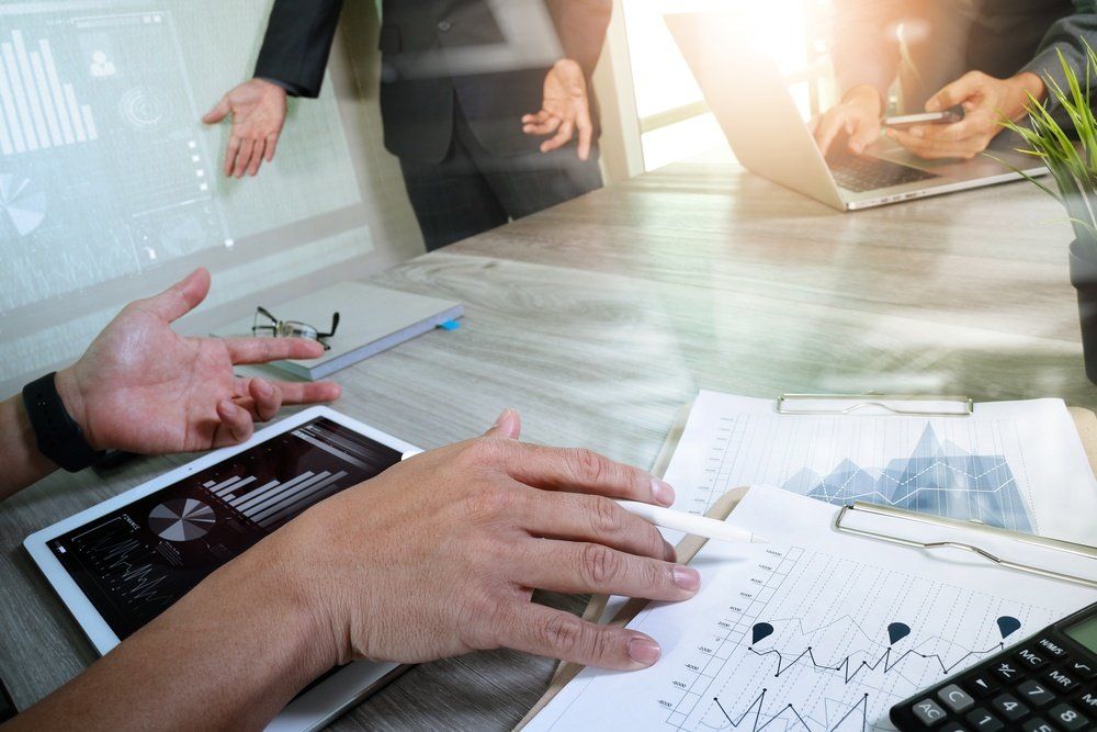 Un grupo de personas está sentada en una mesa mirando una tableta y una calculadora.