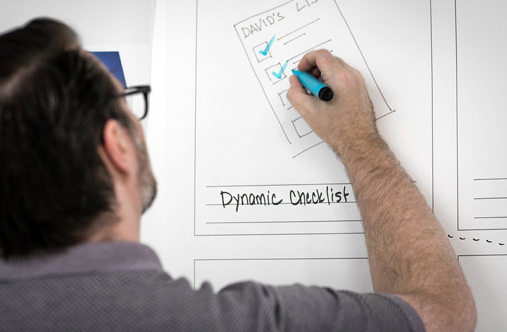 Un hombre está escribiendo una lista de verificación dinámica en una pizarra blanca.