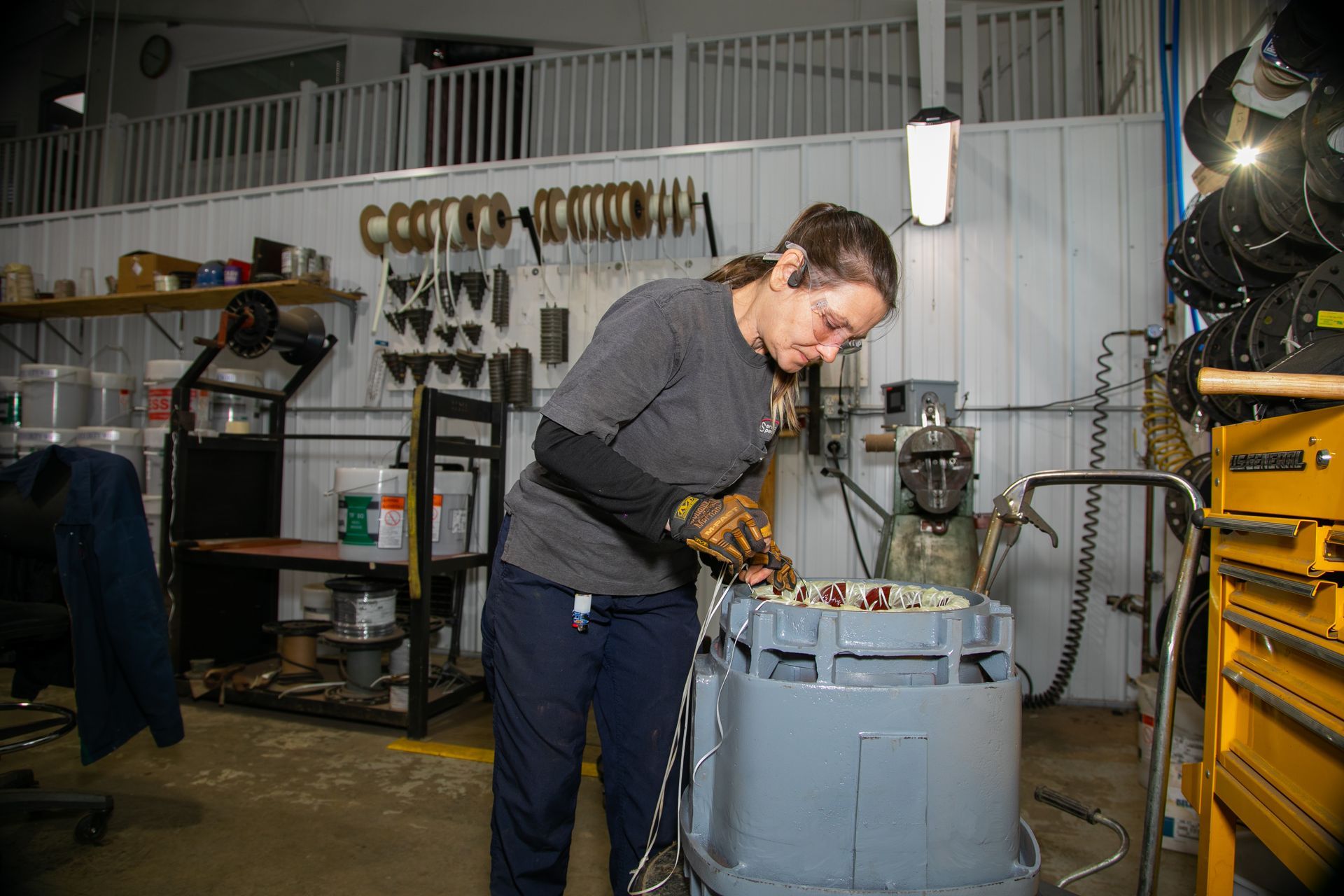 Person working with tools at a workbench in a cluttered workshop