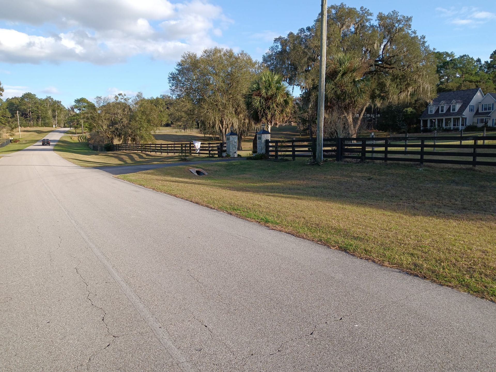 A road with a fence and a house in the background