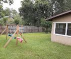 A backyard with a swing set and a house in the background.
