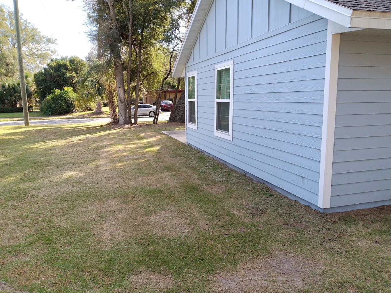 A small house with a lot of windows is sitting on top of a lush green lawn.