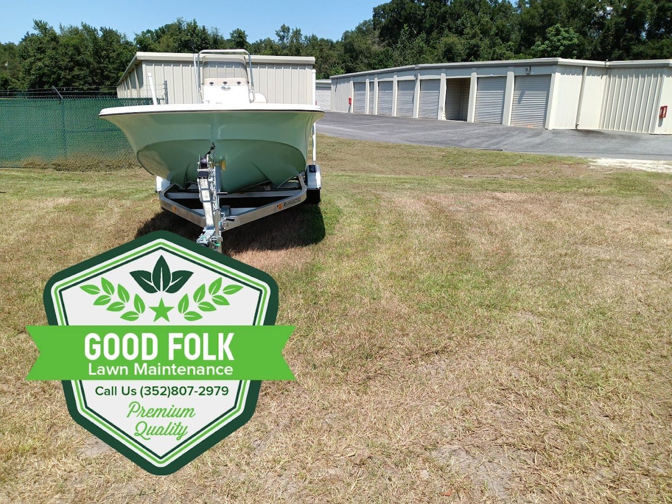 A boat is parked in a grassy field with a good folk lawn maintenance badge.