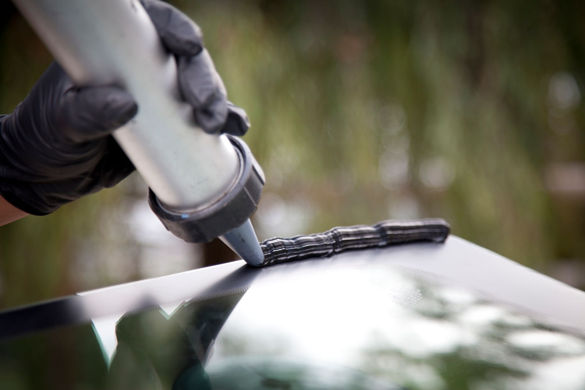 Close-up of technician performing auto glass replacement on damaged windshield.