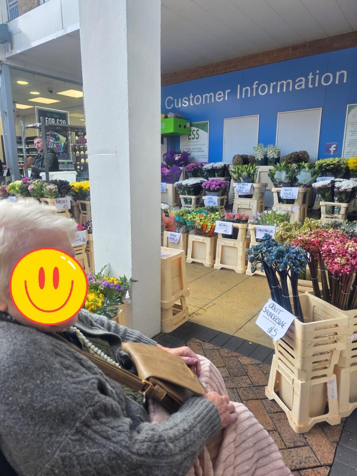 Person in front of a flower stand with wooden crates shopping 