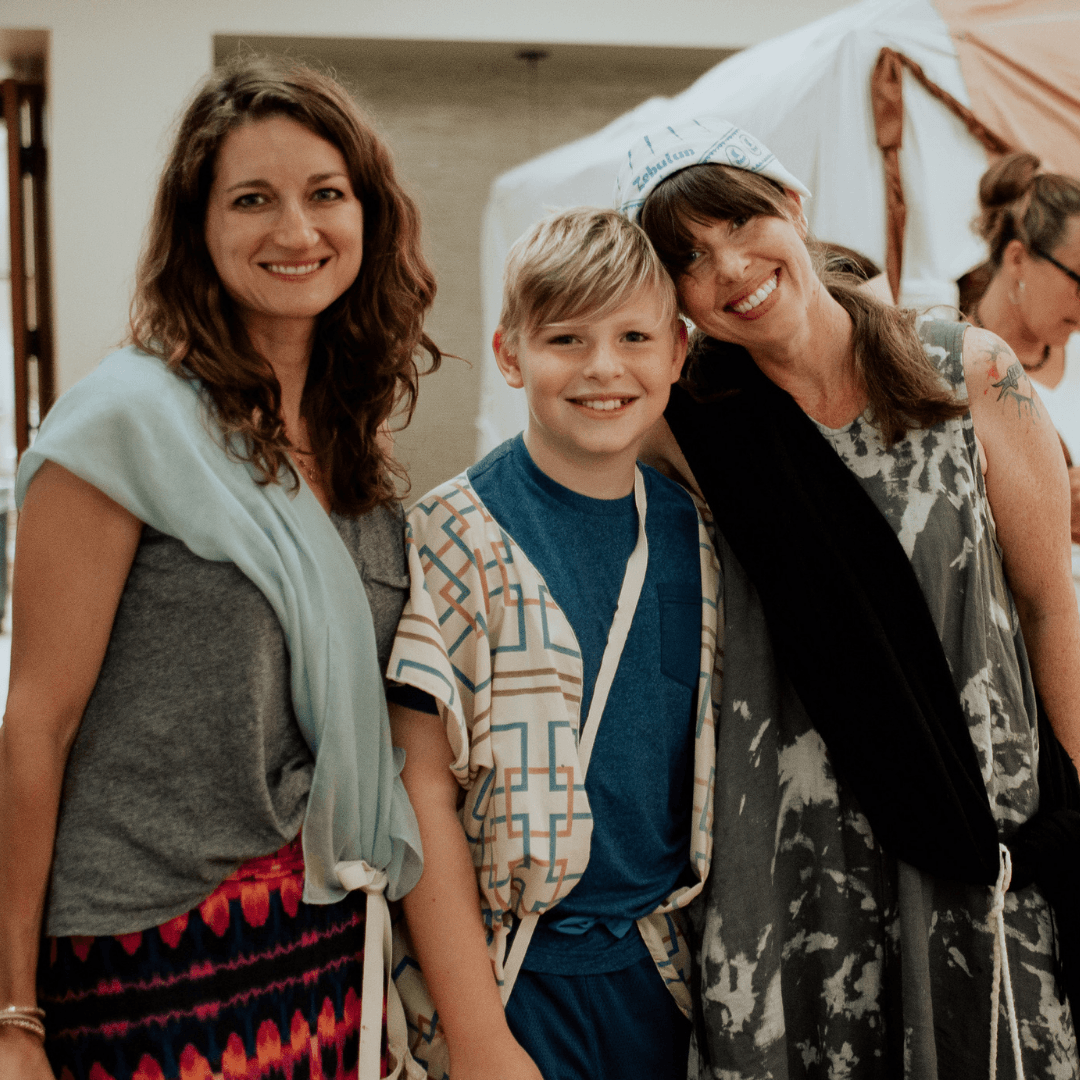 Three women and a boy posing for a picture with the boy wearing a blue shirt with the letter j on it
