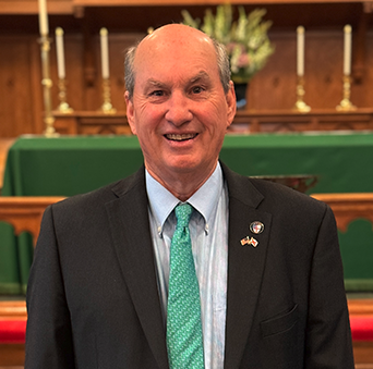 A man in a suit and tie is standing in front of an altar.