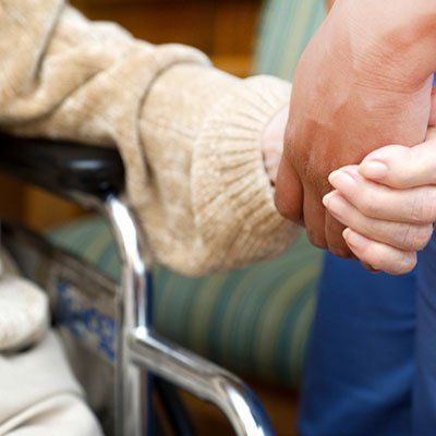 A person in a wheelchair is holding another person 's hand.