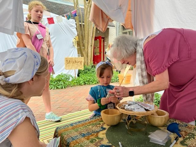 A woman is sitting at a table with bowls and a child.