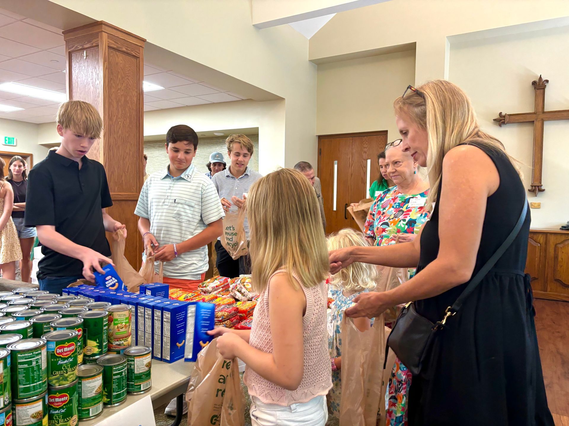 A group of people are standing around a table with cans of food.