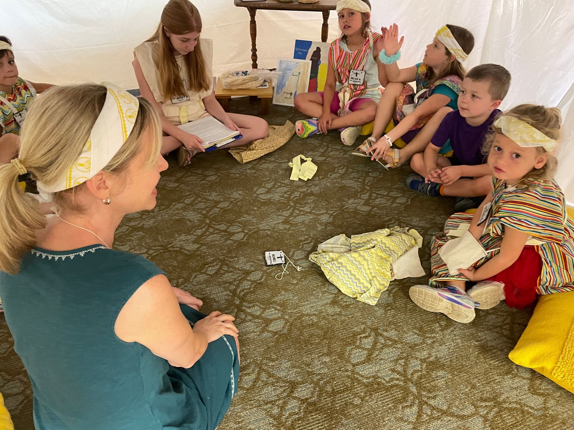 A woman is sitting in a circle with a group of children.