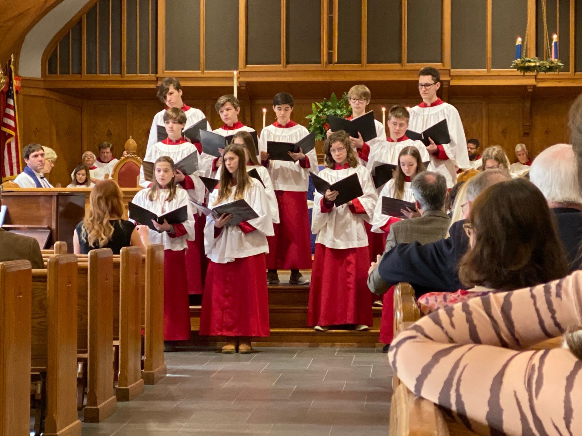 A choir is singing in a church with people sitting in the pews.