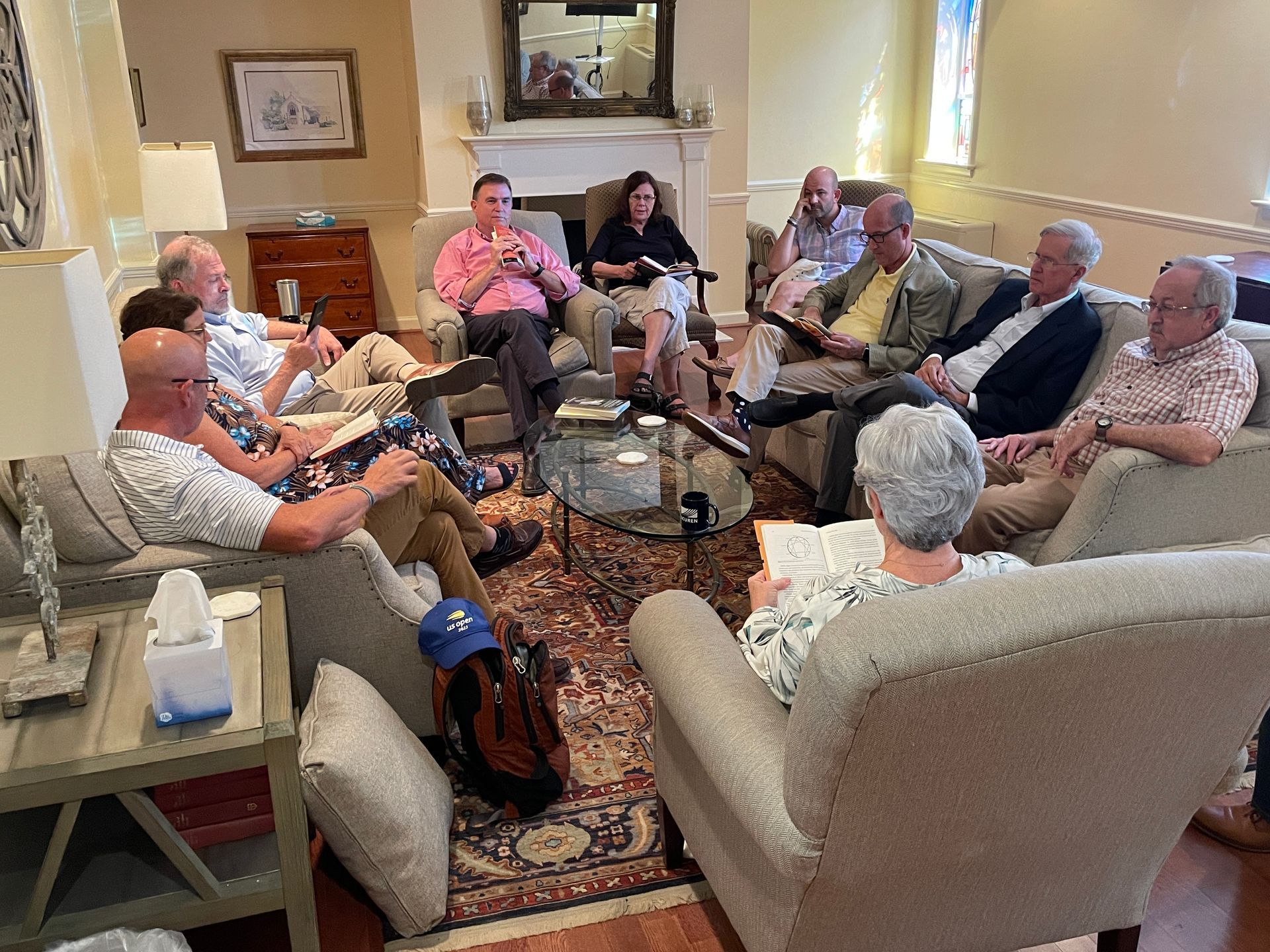 A group of people are sitting around a table in a living room.