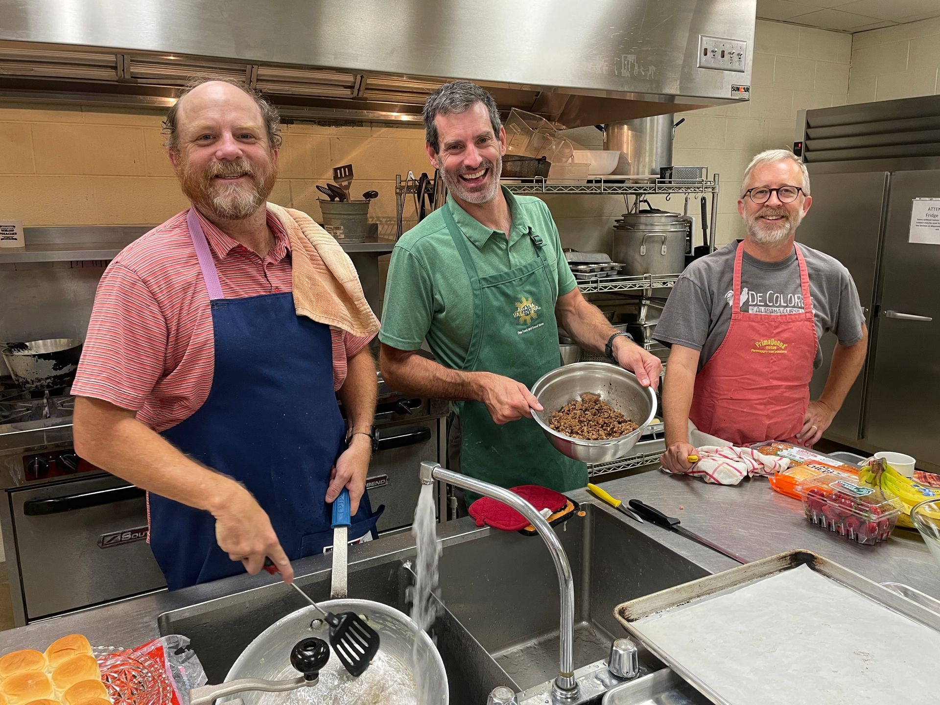 Three men are standing in a kitchen preparing food.