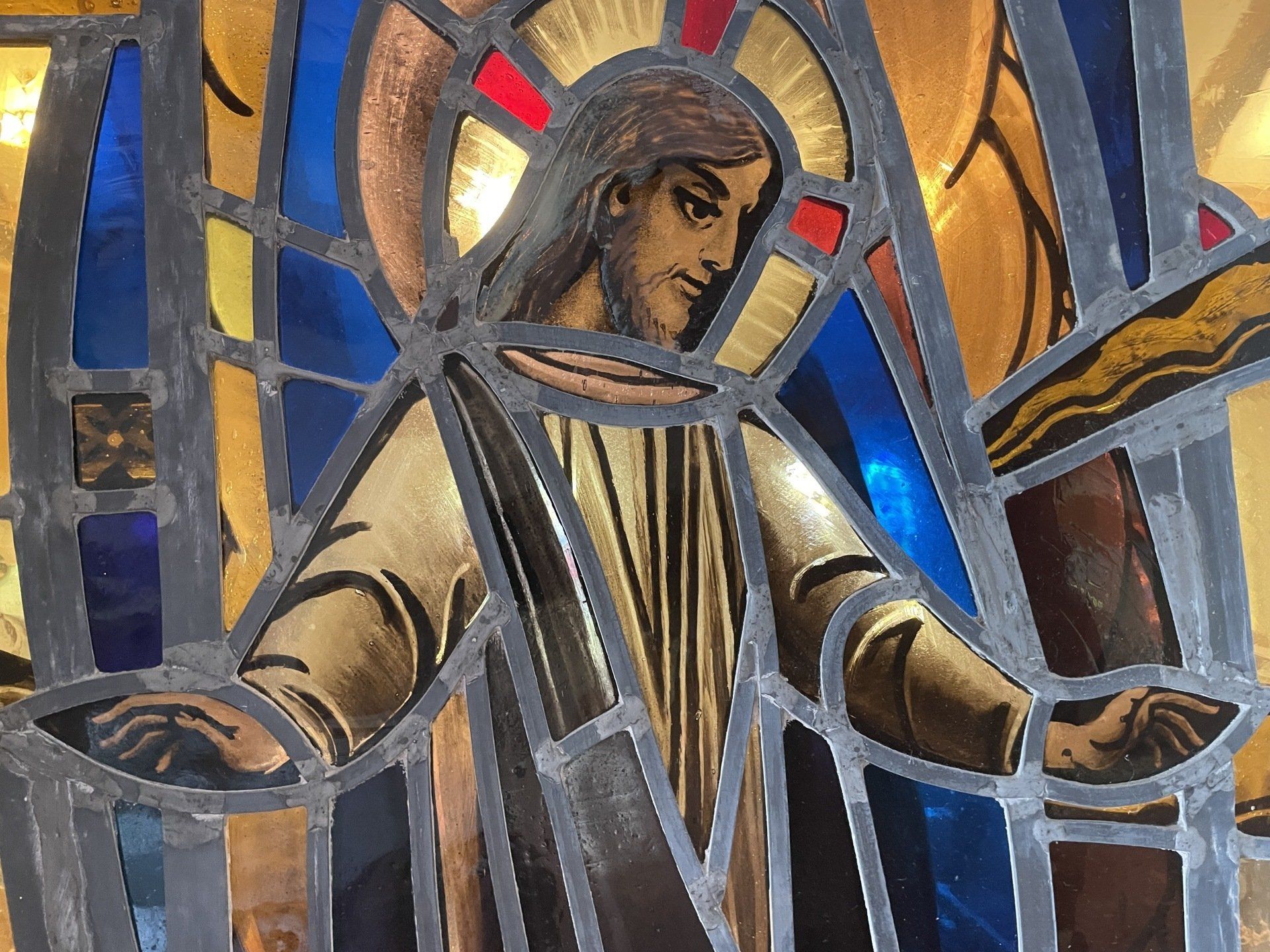 A stained glass window of jesus holding a cross