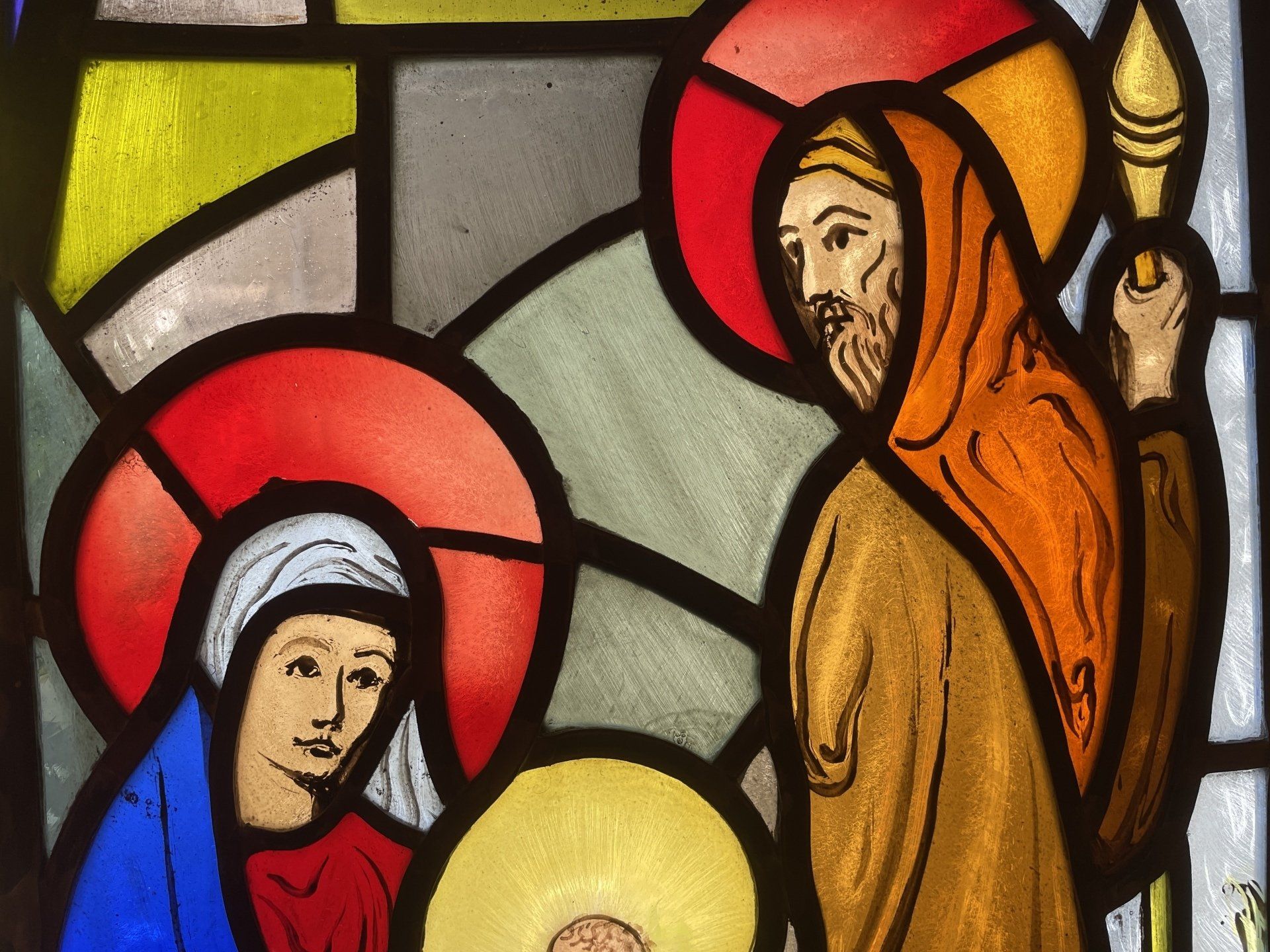 A stained glass window shows a nativity scene