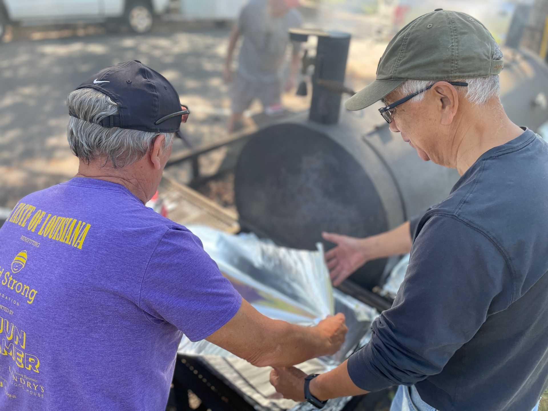 Two men are standing next to each other in front of a grill.