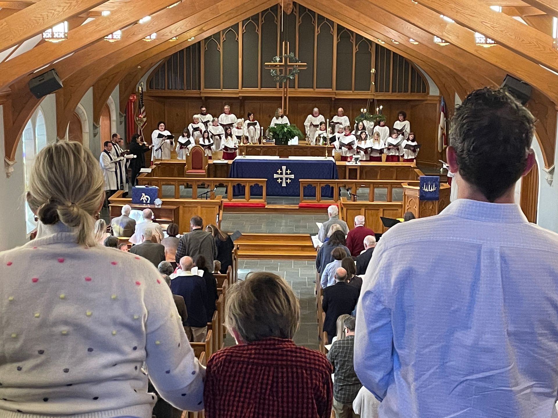 A group of people are standing in a church watching a service.