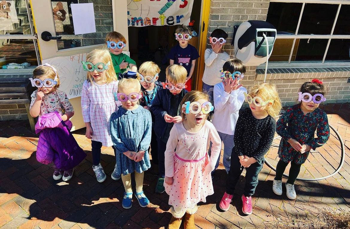 A group of children wearing sunglasses are standing in front of a building.