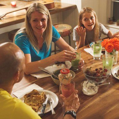 A group of people are sitting at a table with food and drinks