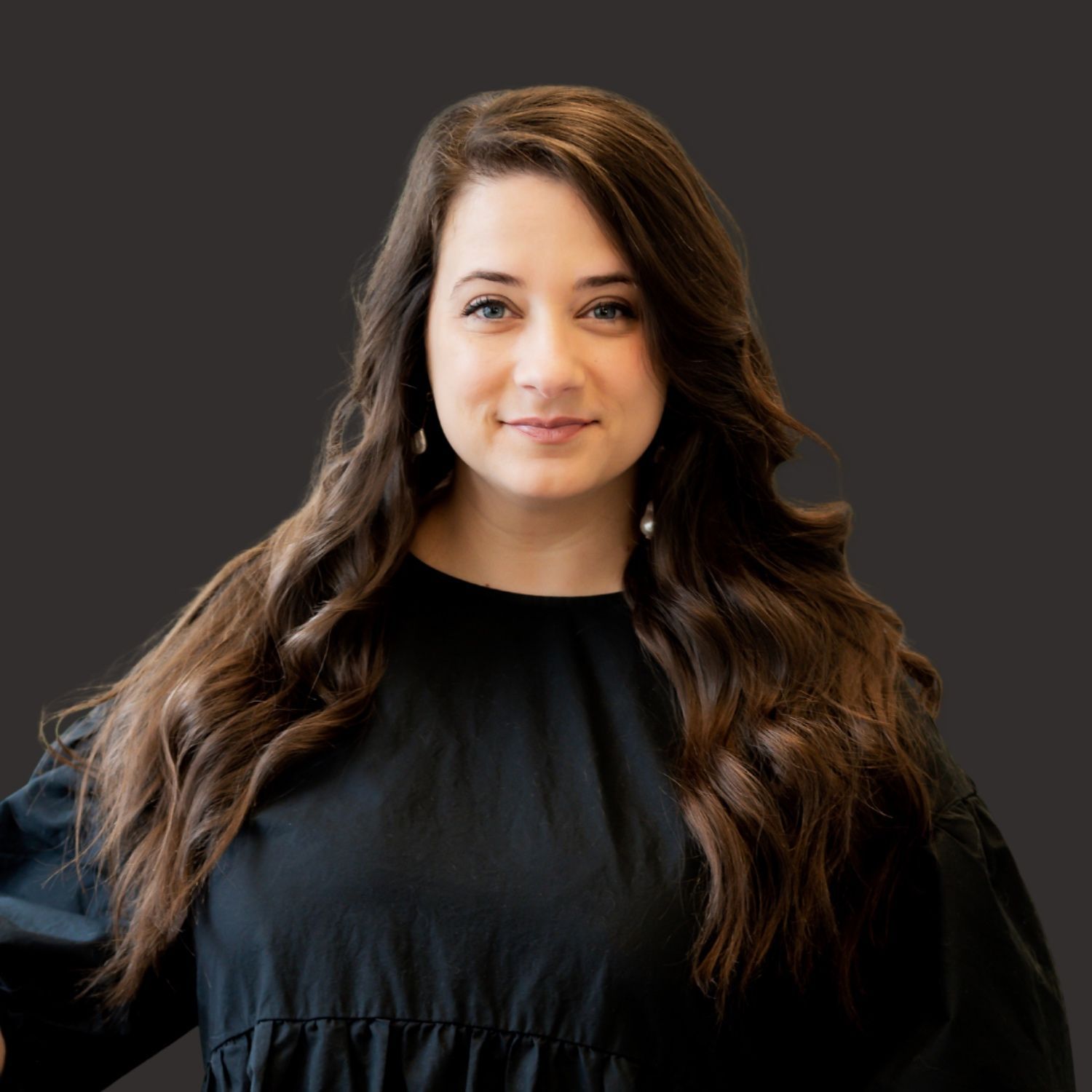 A woman in a white jacket is smiling in front of a church altar.