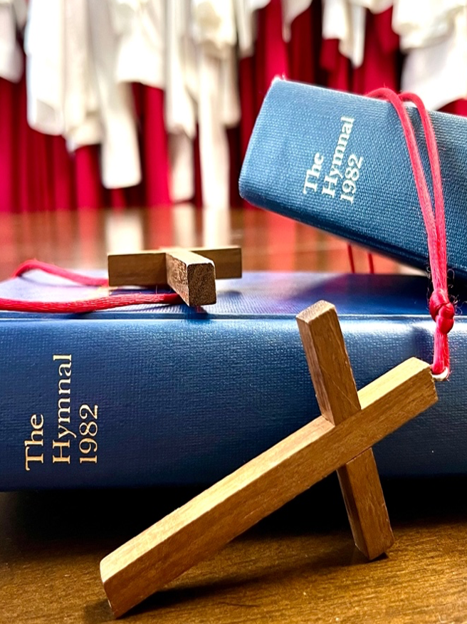 A wooden cross sits on top of a blue hymnal book
