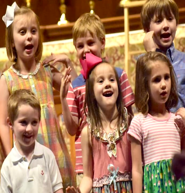 A group of children are singing together in a church choir.