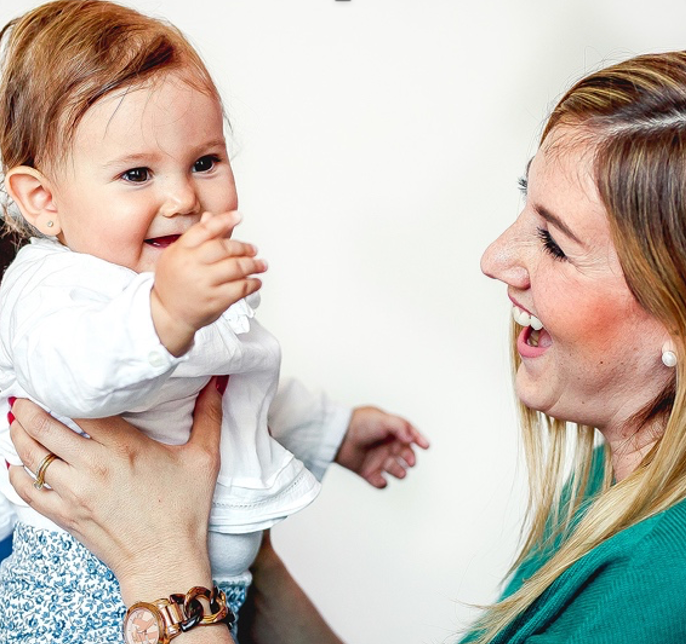 A woman is holding a baby in her arms and smiling.