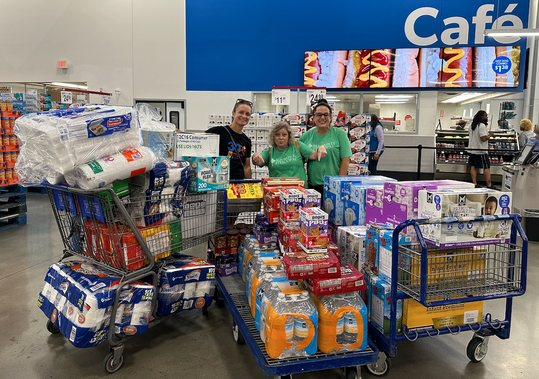A group of people are standing next to shopping carts filled with toilet paper in a store.