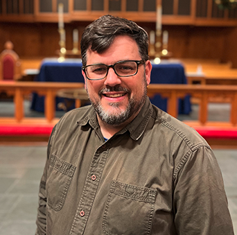 A woman in a black sweater is standing in front of an altar in a church.