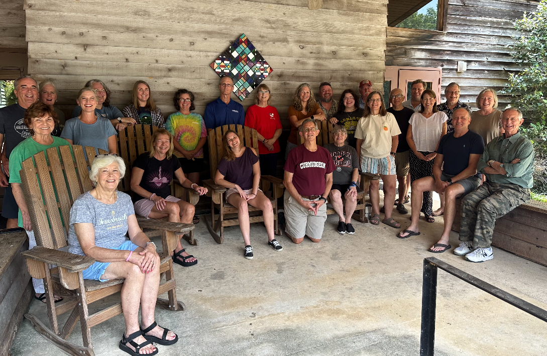 A group of people are sitting in rocking chairs on a porch.