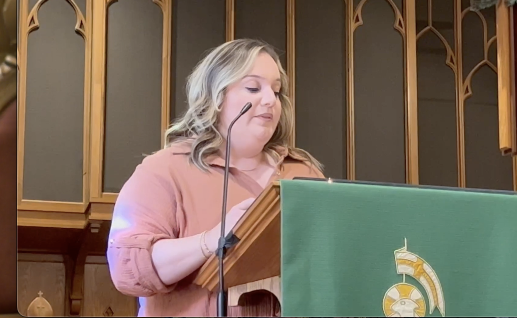 A woman is giving a speech at a podium in a church.