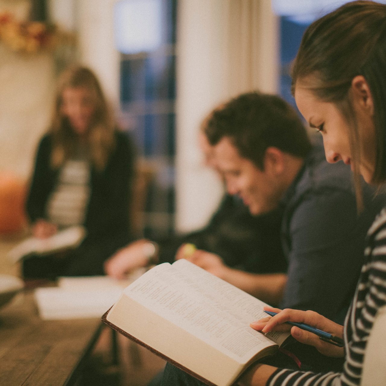 A woman is reading a book with a pen in her hand