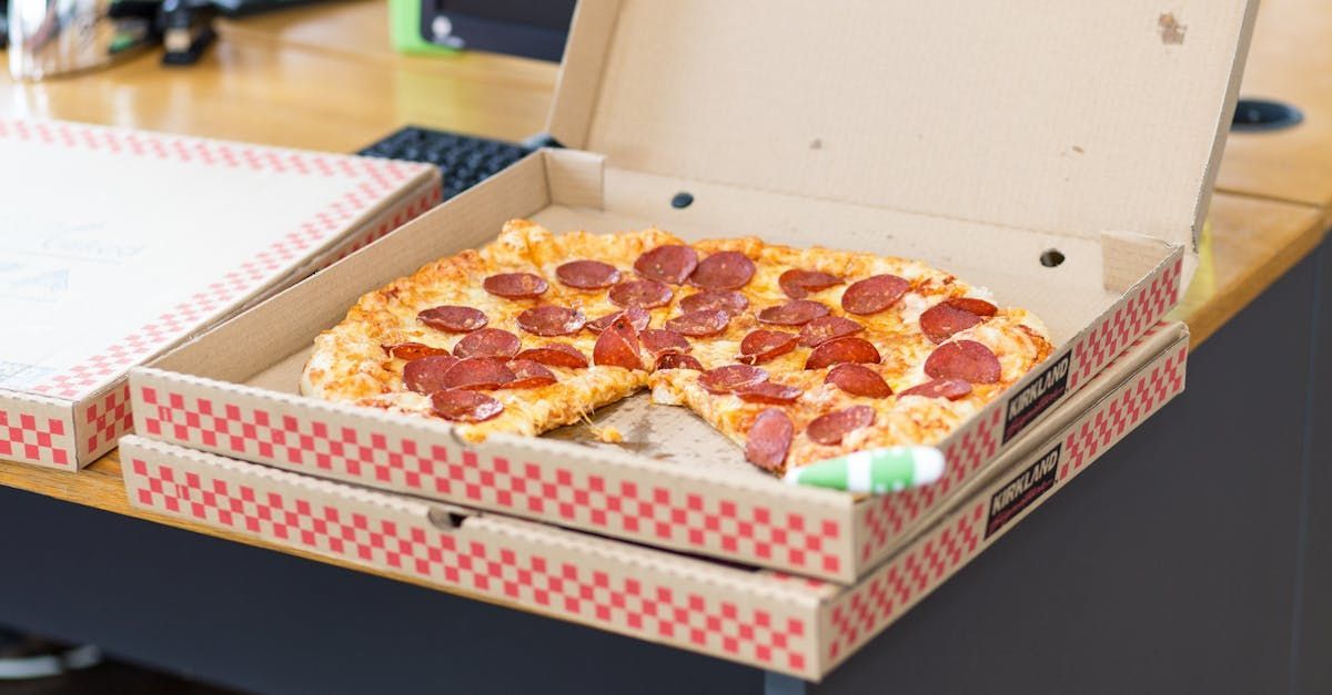 A pepperoni pizza is in a cardboard box on a table.