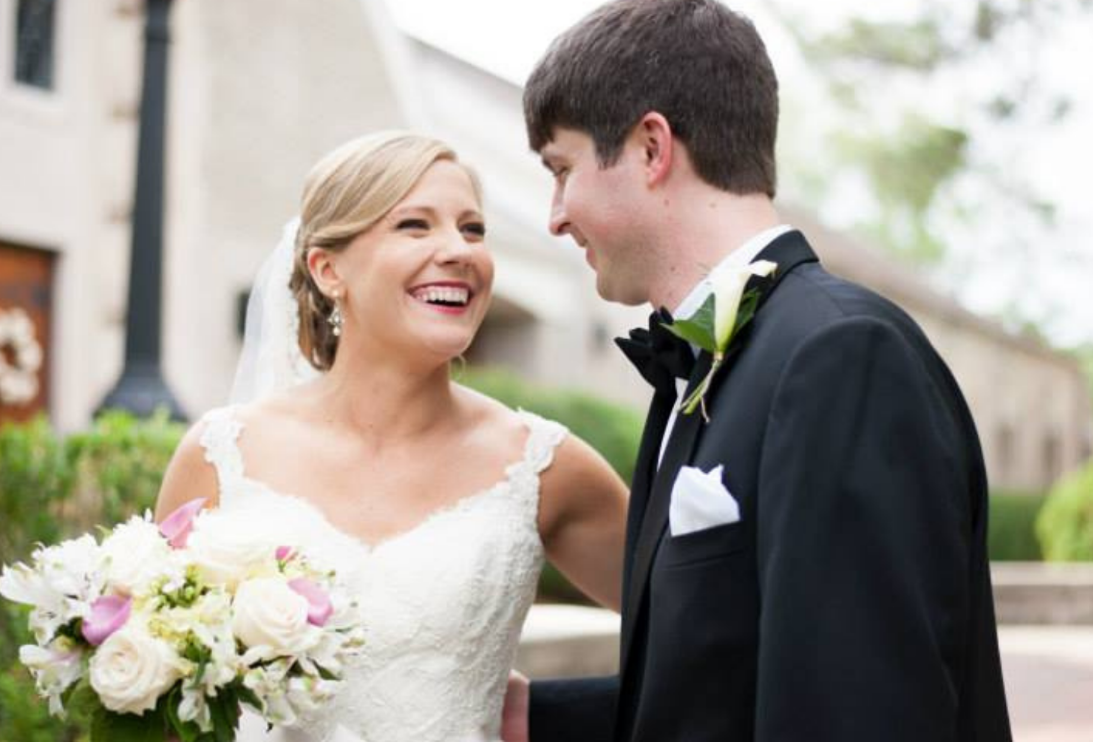A bride and groom are looking at each other and smiling.