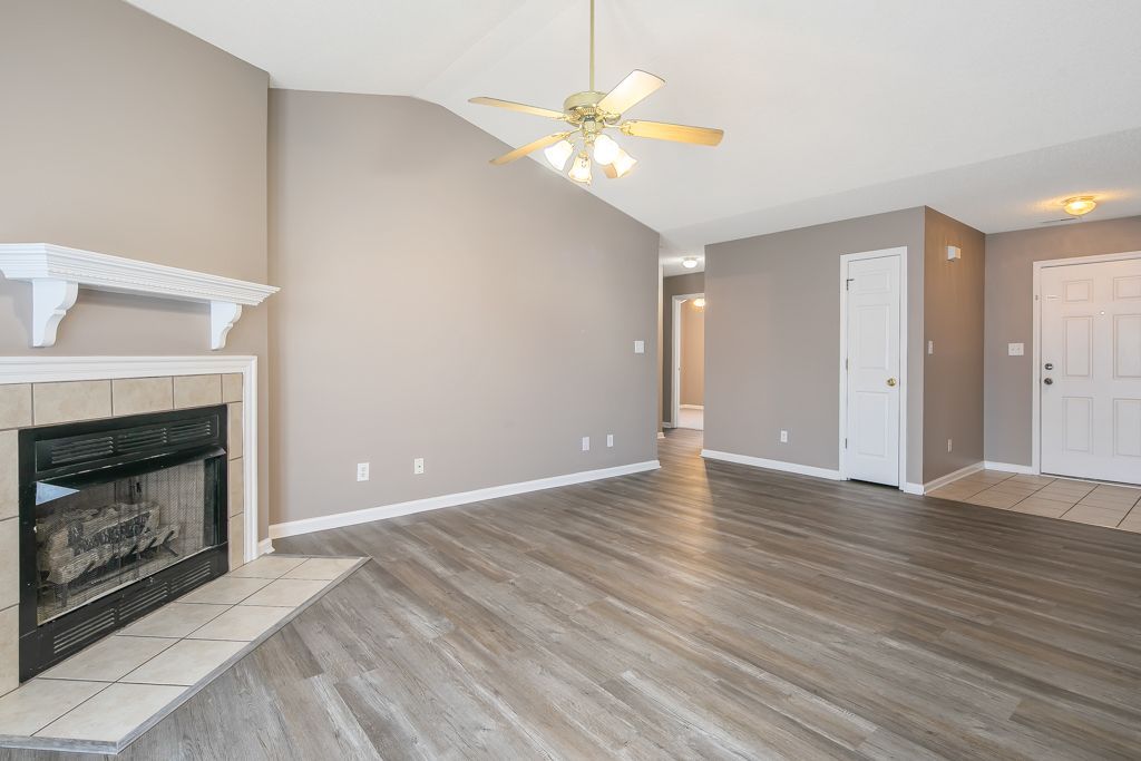 Empty living room with fireplace, hardwood floors, and neutral walls.